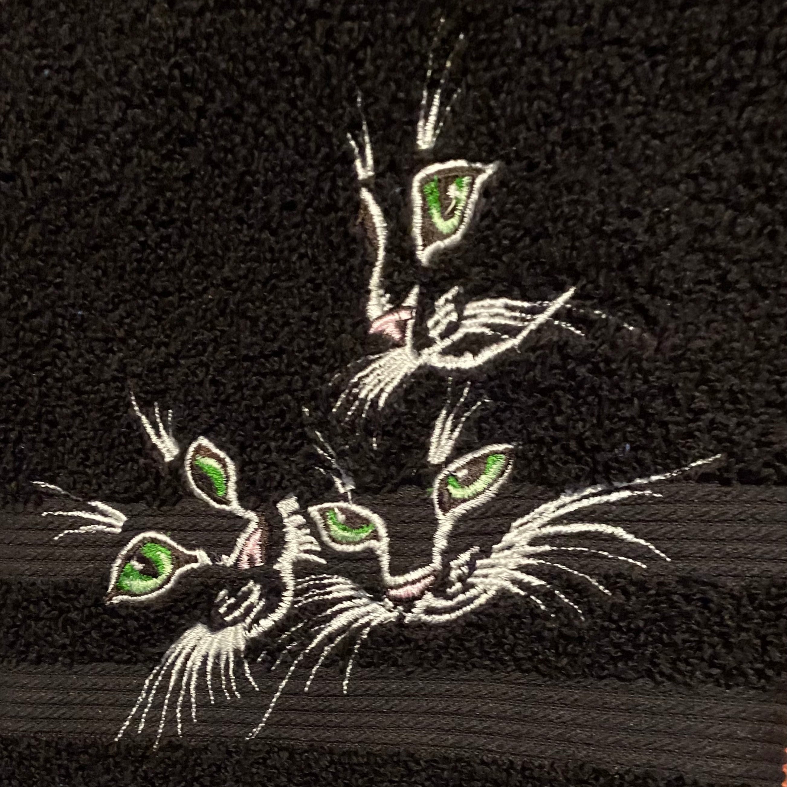 Embroidered design of a cat on a black fabric background